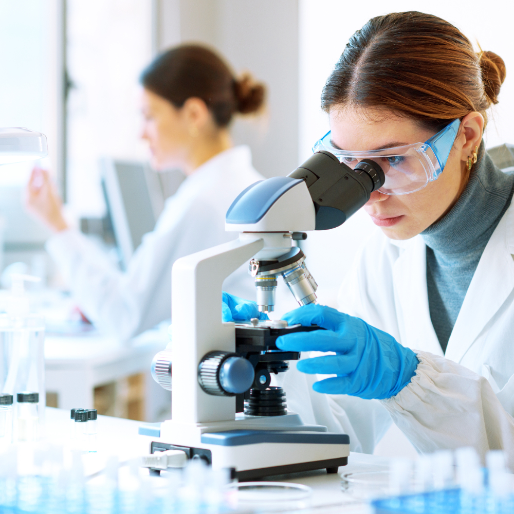 一位身穿实验服的科学家正在显微镜下观察样本。